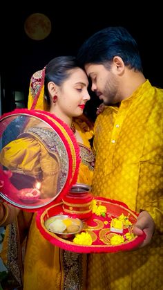 a man and woman standing next to each other holding a tray with food on it