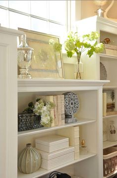 a white book shelf filled with books and vases