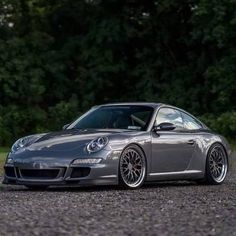 a silver sports car parked in front of some trees