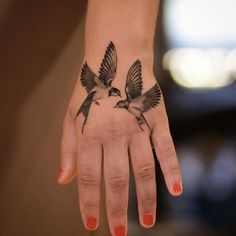 a woman's hand with two birds on it