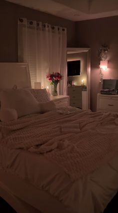 a bed with white sheets and pillows in a bedroom next to a window at night