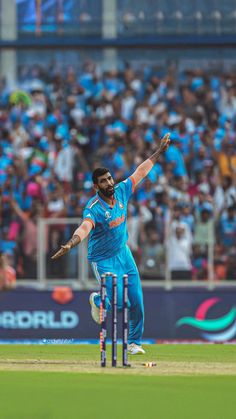 a man in blue uniform playing a game of cricket with people watching from the stands