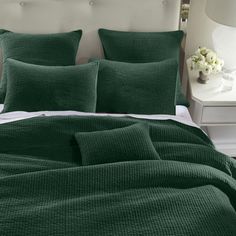 a bed with green bedspread and pillows