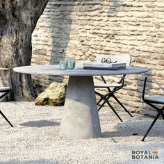 an outdoor table and chairs are shown in front of a stone wall with a tree