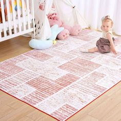 a baby sitting on the floor in front of a crib