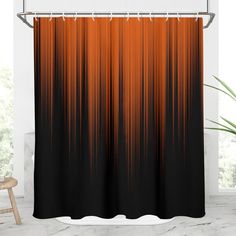 an orange and black shower curtain hanging on a bathroom wall next to a chair in front of a window