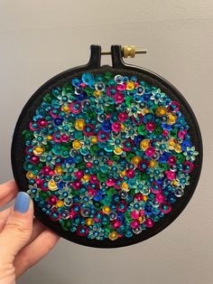 a person holding up a colorful beaded purse with buttons on the front and sides