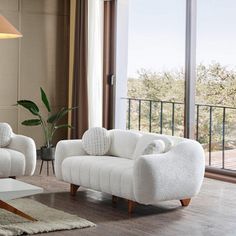 a living room with two white chairs and a coffee table in front of a large window