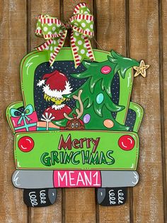 a christmas decoration hanging on the side of a wooden fence with a merry grinmas sign