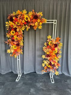 two white metal stands with flowers and leaves on them in front of a gray backdrop