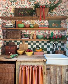 the kitchen is decorated with colorful wallpaper and wooden shelves, along with hanging fruit baskets