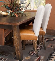 a wooden table with two chairs next to it and a vase filled with flowers on top