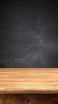 an empty wooden table in front of a chalkboard