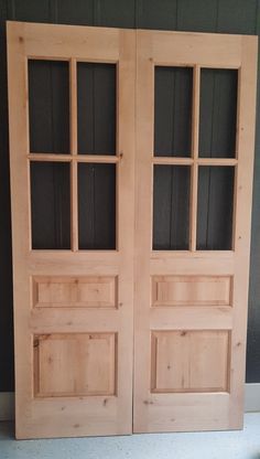 two wooden doors sitting next to each other on top of a floor in front of a wall