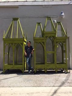 a man standing next to some green wooden structures