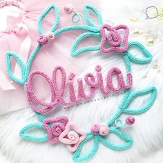 a pink and blue embroidered name on a white furnishce with pearls around it