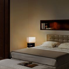 a large bed sitting next to a night stand with a lamp on top of it