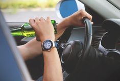 a person sitting in a car with a beer bottle and a watch on their wrist