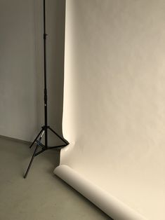 an empty photo studio with a white wall and black tripod on the floor in front of it