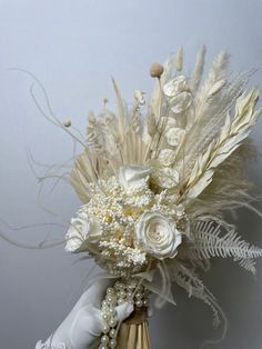 a bridal bouquet with white flowers and feathers