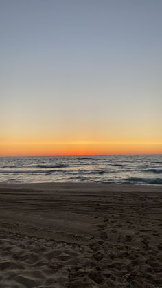 the sun is setting over the ocean on the beach