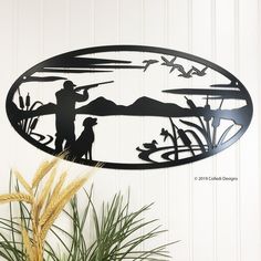 a metal wall art depicting two people and a dog on a lake with mountains in the background