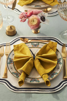 a place setting with yellow napkins and silverware