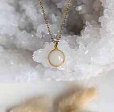 a gold necklace with a white stone in the center on top of some crystals and fur