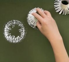 a hand is holding some white toothbrushes on a green surface next to two other items