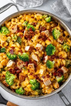 a skillet filled with macaroni and cheese, broccoli and chicken