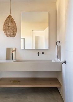 a bathroom with a sink, mirror and hanging light fixture in the middle of it