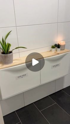 a planter with two plants on top of it in front of a white wall