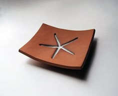 a wooden plate with silver starfish on it sitting on a white table top next to a cup