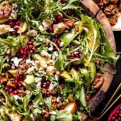 a salad with apples, avocado, walnuts and feta cheese in a wooden bowl