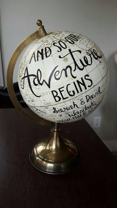 a white and gold globe with writing on it sitting on top of a wooden table