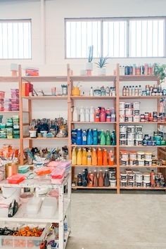 the shelves are filled with many different types of paint and other things to use in this room