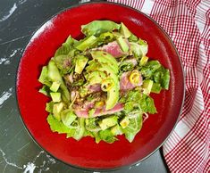 a red plate topped with lettuce and meat on top of a black table