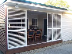 a small white house with shutters on the front and side doors open to let in light