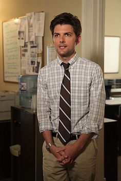 a man standing in an office wearing a tie