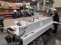 three men in hardhats working on an assembly line