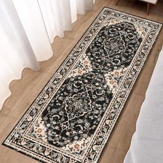 a black and beige rug on the floor in front of a white window with curtains