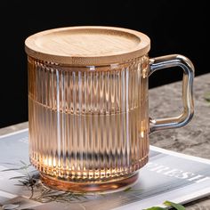 a glass mug sitting on top of a table next to a book and planter