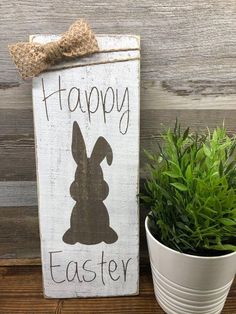 a sign that says happy easter next to a potted plant on a wooden table