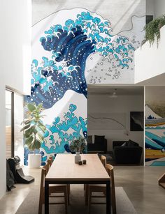 a dining room table and chairs in front of a wall with an ocean wave painted on it