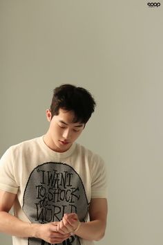 a young man standing in front of a white wall looking at his cell phone while wearing a t - shirt with the words i want to destroy york written on it