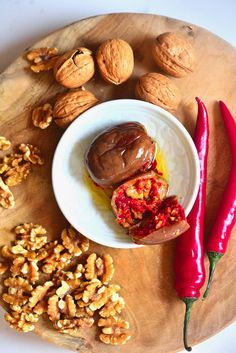 some nuts and other food items on a wooden platter next to a hot pepper