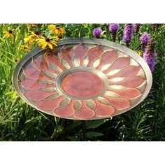 a decorative glass plate sitting in the middle of some flowers