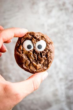 a cookie with eyes and googly eyes is held up in front of the camera