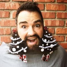 a man with long hair and beard wearing fake christmas trees on his head is making a funny face