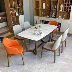 a dining table with orange chairs and white marble top